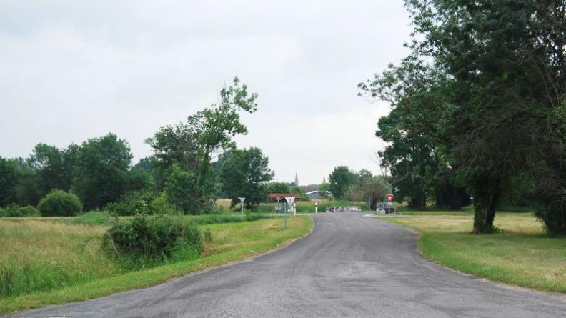 Vue depuis le canal de Ceinture : les pentes s'élèvent doucement, l'église signale le bourg de Braud derrière les arbres, légèrement surélevé - Braud-et-Saint-Louis
