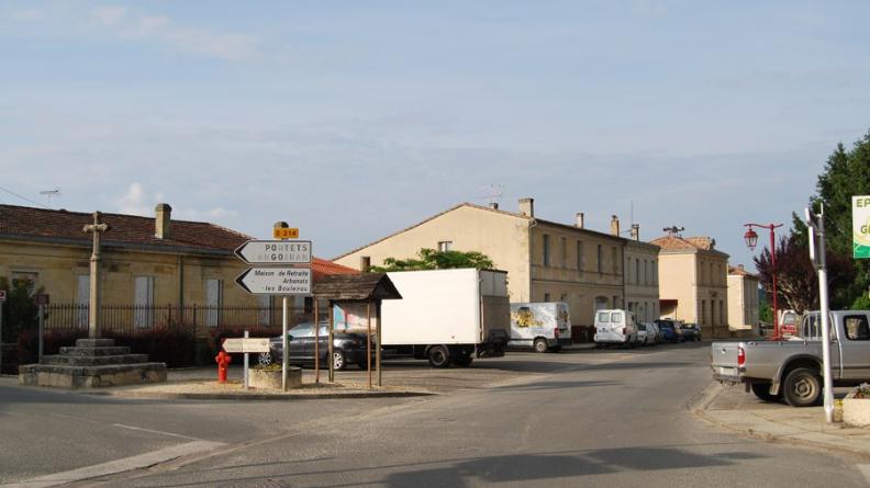 Arbanats vers 1910 et aujourd'hui - Les espaces publics arborés d'Arbanats ont été supplantés par des places de stationnement.