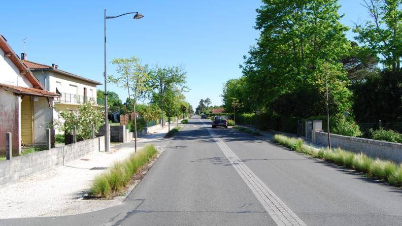 Quelques plantations basses suffisent à agrémenter cette rue et à délimiter l'espace piéton, tout en restant dans un aménagement à l'image rurale. Le pavage au centre de la chaussée évite le marquage routier banal ; les trottoirs sont différenciés de la chaussée par les matériaux et restent perméables. L'absence de bordure permet aux eaux de ruissellement d'arroser les plantes herbacées. La route est plantée - Hourtin