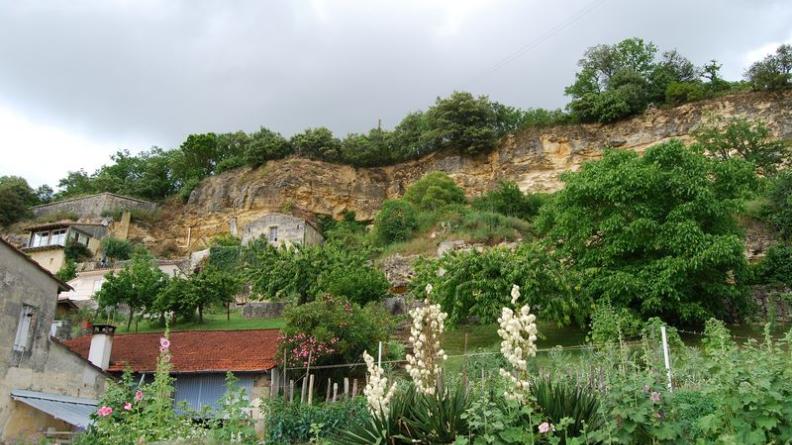 Jardins, constructions et falaise se mêlent en une façade troglodytique complexe - Gauriac
