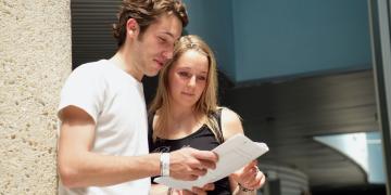 un jeune couple consulte un document en recherche d'informations sur le RSA