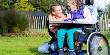 une femme s'occupe d'une petite fille handicapée sur une chaise roulante