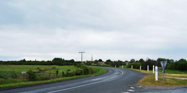 En arrivant depuis le nord, le village se signale par une densité végétale plus importante et par la silhouette de son clocher - Talais 