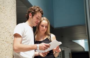 un jeune couple consulte un document en recherche d'informations sur le RSA